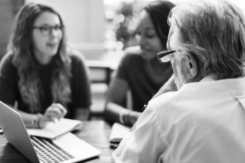 Picture of tutor and two young people in discussion around a laptop