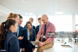 A male teacher talking to a group of students in a science room